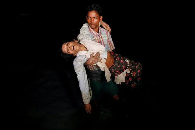 Nobi Hossain wades through the water carrying his elderly relative Sona Banu as hundreds of Rohingya refugees arrive under the cover of darkness by wooden boats from Myanmar to the shore of Shah Porir Dwip, in Teknaf, near Cox's Bazar in Bangladesh, September 27, 2017. (Photo by Damir Sagolj/Reuters)