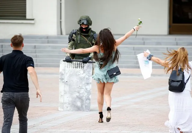 Participants approach a law enforcement officer with open arms during an opposition demonstration to protest against police violence and to reject the presidential election results near the Government House in Independence Square in Minsk, Belarus on August 14, 2020. (Photo by Vasily Fedosenko/Reuters)