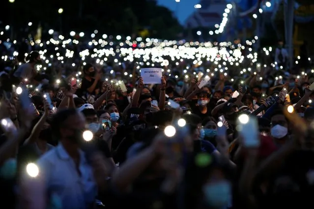 Pro-democracy protesters use mobile phones as flashlights at a rally as one of them is holding a placard at a rally to demand the government to resign, to dissolve the parliament and to hold new elections under a revised constitution, near the Democracy Monument in Bangkok, Thailand, August 16, 2020. (Photo by Soe Zeya Tun/Reuters)