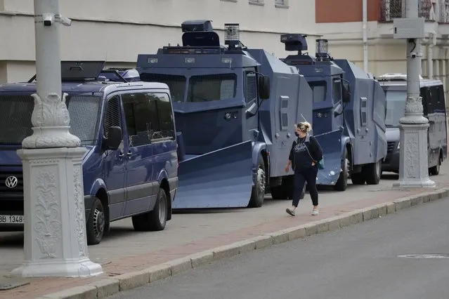 A woman walks past parked police vehicles during a rally by Belarusian school teachers and Belarusian opposition supporters in the center of Minsk, Belarus, Tuesday, August 25, 2020. Authorities in Belarus are steadily cranking up the pressure on protesters who are pushing for the resignation of the country's authoritarian leader. They have jailed several opposition activists, summoned others for questioning and selectively ordered demonstrators to appear in court. (Photo by Sergei Grits/AP Photo)