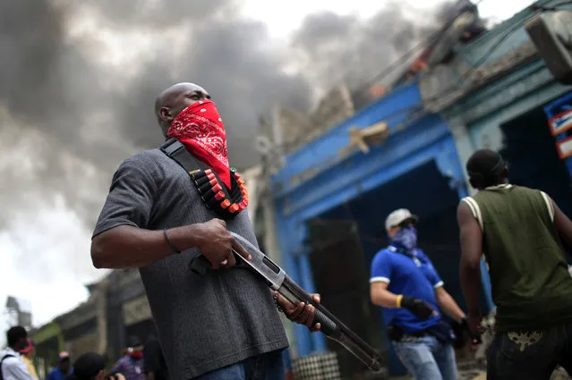 A private security guard stands outside a  burning store in downtown Port-au-Prince, Haiti, Januaary 19, 2010. (Photo by Carlos Barria/Reuters)