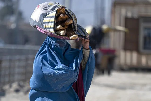 An Afghan woman carries bread on a tray, along a street in Kabul on January 3, 2023. (Photo by Wakil Kohsar/AFP Photo)