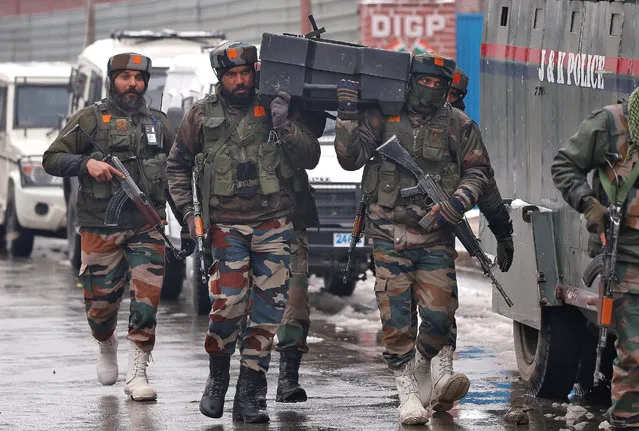 Indian army soldiers carry a box containing bulletproof shields near the site of a gunbattle with suspected militants in Srinagar February 12, 2018. (Photo by Danish Ismail/Reuters)