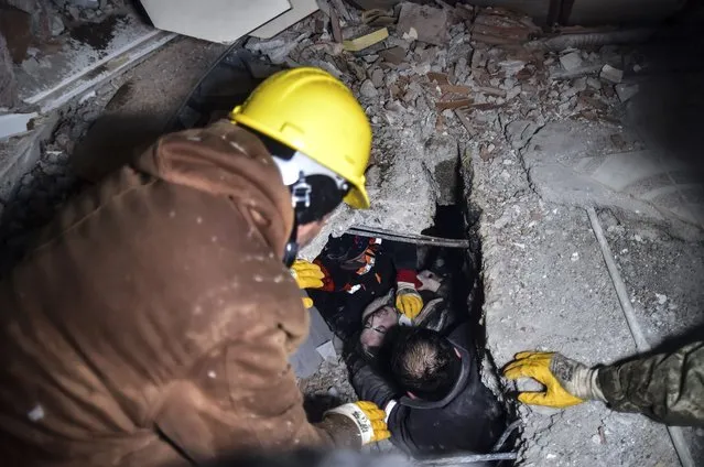 Emergency workers and medics rescue a woman out of the debris of a collapsed building in Elbistan, Kahramanmaras, in southern Turkey, Tuesday, February 7, 2023. Rescuers raced Tuesday to find survivors in the rubble of thousands of buildings brought down by a 7.8 magnitude earthquake and multiple aftershocks that struck eastern Turkey and neighboring Syria. (Photo by Ismail Coskun/IHA via AP Photo)