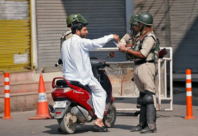 An Indian policeman checks a document of a Kashmir man at a barricade during a curfew in Srinagar September 30, 2016. (Photo by Danish Ismail/Reuters)