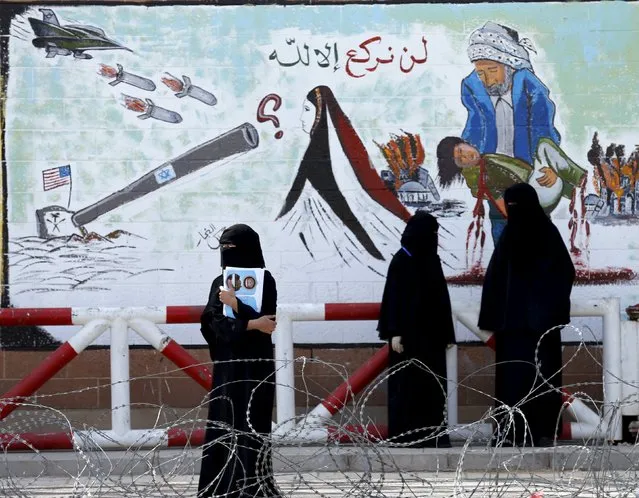 Women stand next a graffiti painted by pro-Houthi activists on the gate of the Saudi embassy in Yemen's capital Sanaa October 21, 2015. The writing reads, "We will kneel only to Allah". (Photo by Khaled Abdullah/Reuters)