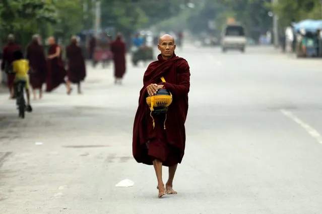 A Buddhist monk walks with his alms bowl early morning in Mandalay October 7, 2015. (Photo by Jorge Silva/Reuters)