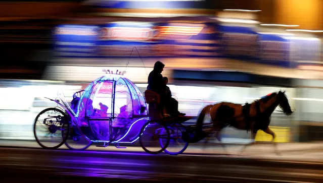 Children travel on an illuminated horse drawn carriage as they pass under the illuminations on the promenade in Blackpool, northern England October 13, 2016. (Photo by Phil Noble/Reuters)