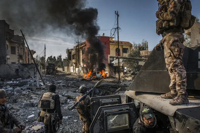 The battle for Mosul: Iraqi Special Forces soldiers survey the aftermath of an attack by an ISIS suicide car bomber, who managed to reach their lines in the Andalus neighborhood, one of the last areas to be liberated in eastern Mosul, January 16, 2017. Iraqi Special Forces soldiers survey the aftermath of an attack by an ISIS suicide car bomber, who managed to reach their lines in the Andalus neighborhood, one of the last areas to be liberated in eastern Mosul. On 10 July 2017, after months of fighting, the Iraqi government declared the city of Mosul fully liberated from ISIS, although fierce fighting continued in pockets of the city. Mosul had fallen to ISIS three years earlier, and the battle to retake it had begun in October 2016. In effect, the reconquering of Mosul comprised two parts: the battle for the eastern half of the city, and that for the west, across the Tigris River. East Mosul was recaptured by the end of January 2017, but the offensive on west Mosul, particularly the densely built-up Old City, proved more difficult. Large areas of the city were left in ruins, and huge numbers of civilians were caught in the crossfire as battle raged. A United Nations report gives an absolute minimum of 4,194 civilian casualties during the conflict, with other sources putting the figure much higher. The Office of the UN High Commissioner for Human Rights pointed to extensive use of civilians as human shields, with ISIS fighters attempting to use the presence of civilian hostages to make certain areas immune from military operations. After months of being trapped in the last remaining ISIS-held areas of the city, the people in west Mosul were severely short of food and water. Those who chose to remain in the city rather than go to one of the many camps for displaced people, initially relied on aid in order to survive. (Photo by Ivor Prickett for The New York Times/World Press Photo)