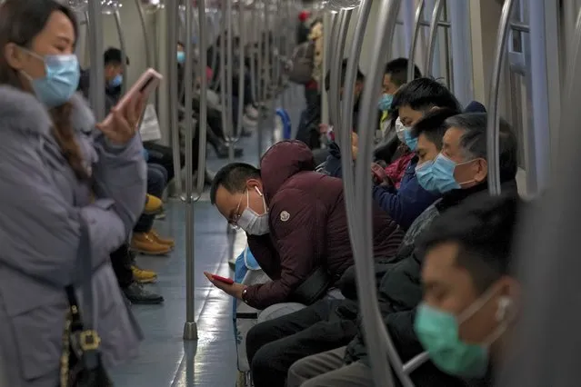 Commuters wearing face masks to help curb the spread of the coronavirus ride in a subway train in Beijing, Monday, December 14, 2020. (Photo by Andy Wong/AP Photo)