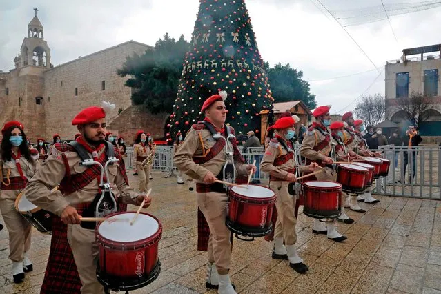 A Palestinian scouts band parades in front of the Church of the Nativity during Christmas celebrations in the biblical city of Bethlehem in the occupied West Bank, on December 24, 2020. In a normal year hundreds of thousands of visitors flood the Palestinian city in the Israeli-occupied West Bank. But with coronavirus restrictions making travel to Bethlehem all but impossible for foreign worshippers, the Church of the Nativity has been eerily calm in the days before Christmas. (Photo by Hazem Bader/AFP Photo)