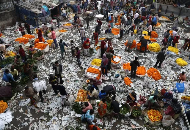 Vendors sell marigold flowers at a wholesale market littered with paper used for packaging in Kolkata, India, Tuesday, December 22, 2020. (Photo by Bikas Das/AP Photo)