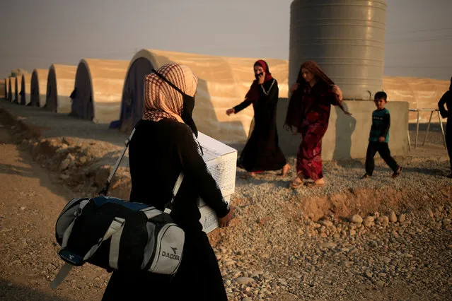 A newly internally displaced woman carries humanitarian package upon her arrival at Al Khazar camp near Hassan Sham, east of Mosul, Iraq October 26, 2016. (Photo by Zohra Bensemra/Reuters)
