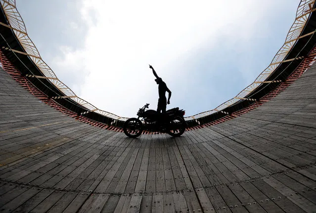 A stuntman performs a test ride on a motorcycle inside the “Well of Death” arena during a fair in Bhaktapur, Nepal April 9, 2018. (Photo by Navesh Chitrakar/Reuters)