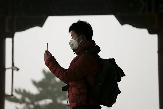 A man wearing protective mask takes pictures of the Forbidden City from the top of Jingshan Park on an extremely polluted day as hazardous, choking smog continues to blanket Beijing, China December 1, 2015. (Photo by Damir Sagolj/Reuters)