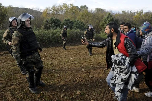 Macedonian police officers block stranded migrants as they attempt to cross the Greek-Macedonian border, near Gevgelija, Macedonia  December 2, 2015. Picture taken from the Greek side of the border. (Photo by Alexandros Avramidis/Reuters)
