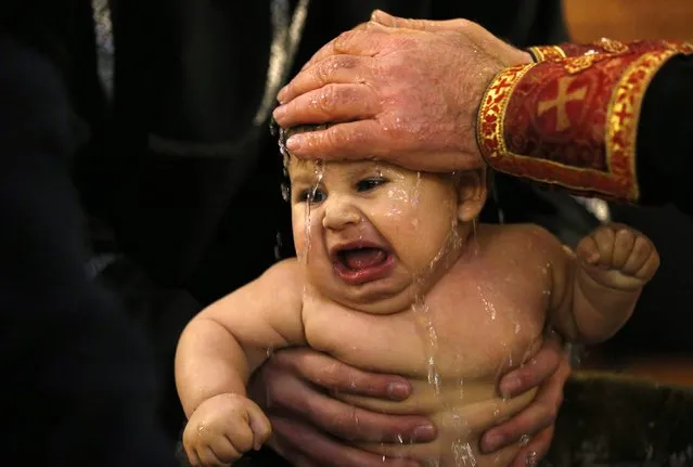 A baby is baptised during a mass baptism ceremony on Epiphany day in Tbilisi, January 19, 2015. (Photo by David Mdzinarishvili/Reuters)
