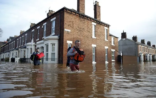 Residents carry their belongings as they walk along a flooded residential street in Carlisle, Britain December 6, 2015. (Photo by Phil Noble/Reuters)