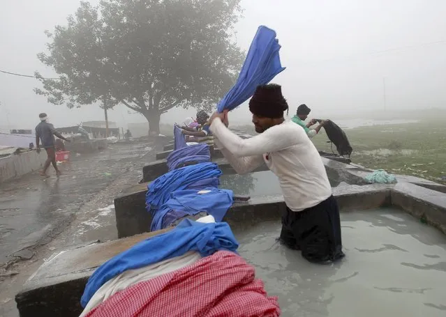 Indian traditional laundrymen known as “dhobis” wash clothes at an open air laundry on a foggy morning in Allahabad, India, December 9, 2015. (Photo by Jitendra Prakash/Reuters)