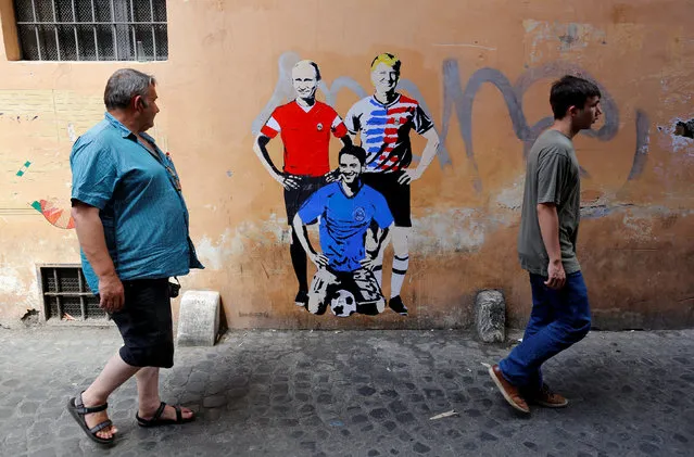 Tourists walk past a mural signed by “TV Boy” and depicting Russian President Vladimir Putin, U.S. President Donald Trump and Italian Prime Minister Giuseppe Conte as soccer players in downtown Rome, Italy June 15, 2018. (Photo by Tony Gentile/Reuters)