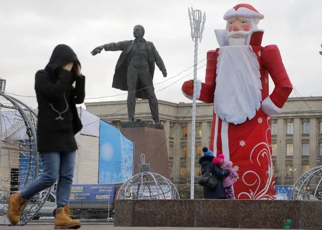 A woman walks past a statue of Soviet Union founder Vladimir Lenin and a figure of Ded Moroz (Grandfather Frost) at a square decorated for the Christmas celebration in St.Petersburg, Russia, Monday, December 21, 2015. (Photo by Dmitry Lovetsky/AP Photo)
