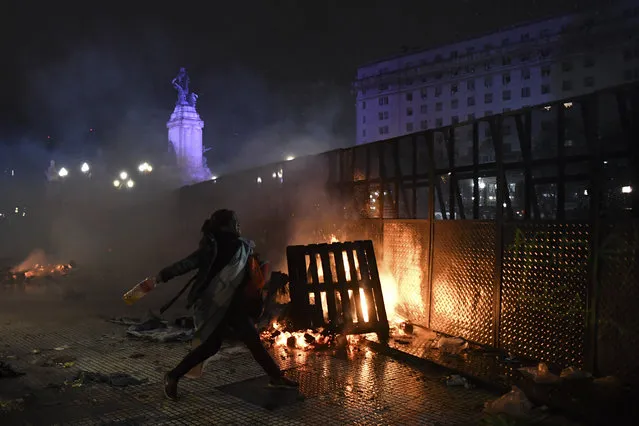 A woman throws a bottle to riot police agents outside the National Congress in Buenos Aires on August 9, 2018, after senators rejected the bill to legalize abortion. Argentine senators on Thursday voted against legalizing abortion in the homeland of Pope Francis, dashing the hopes of women's rights groups after the bill was approved by Congress's lower house in June. According to an official tally, 38 senators voted against, 31 in favor, while two abstained. (Photo by Eitan Abramovich/AFP Photo)