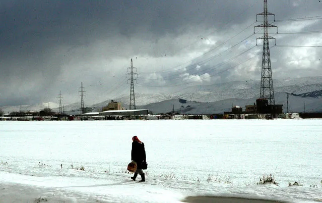 A Syrian refugee man carry bread as he walk in the snow in the Barelias refugee camp in the Bekaa valley, eastern Lebanon, January 2, 2016. According to local reports ongoing snowstorms over the last two days have led to mountain roads in the Bekaa Valley to be closed.  (Photo by Lucie Parsaghian/EPA)