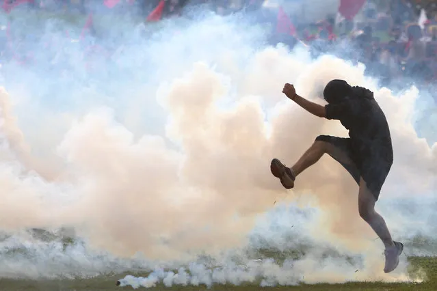 An anti-government demonstrator kicks back a tear gas canister during a clash with riot policemen during a protest against a constitutional amendment, known as PEC 55, that limits public spending, in front of Brazil's National Congress in Brasilia, Brazil November 29, 2016. (Photo by Adriano Machado/Reuters)