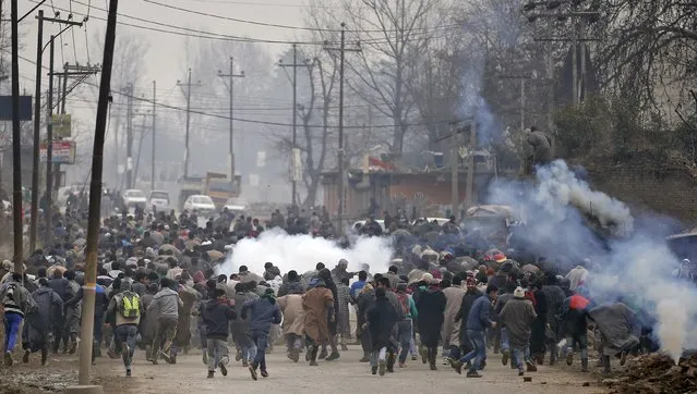 Protesters run for cover amid teargas fired by Indian police after the funeral of Sajad Ahmad Bhat, a suspected militant, on the outskirts of Srinagar, January 12, 2016. (Photo by Danish Ismail/Reuters)