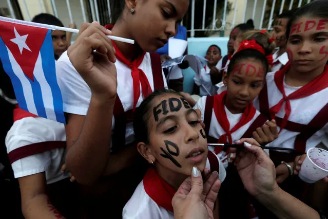 School girls paint their faces while waiting for the ashes of Cuba's former President Fidel Castro to pass during a journey to the eastern city of Santiago de Cuba, in Bayamo, Cuba, December 2, 2016. (Photo by Edgard Garrido/Reuters)