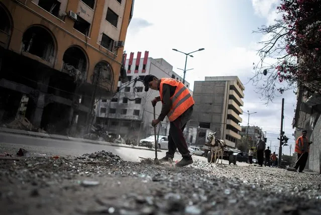 Palestinian municipal workers clean the streets following a cease-fire reached after an 11-day war between Gaza's Hamas rulers and Israel, in Gaza City, Friday, May 21, 2021. (Photo by Khalil Hamra/AP Photo)