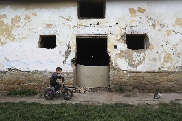 Milan Bastyur, a 4 year old Hungarian Roma child, rides a bike outside his family's home in Bodvaszilas, Hungary, Monday, April 12,2021. Many students from Hungary's Roma minority do not have access to computers or the internet and are struggling to keep up with online education during the pandemic. Surveys show that less than half of Roma families in Hungary have cable and mobile internet and 13% have no internet at all. (Photo by Laszlo Balogh/AP Photo)