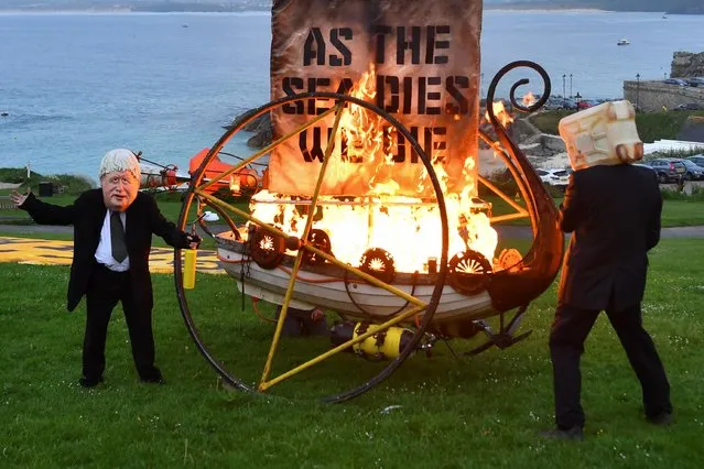 Climate change activist ceremoniously burn a boat in St. Ives, during the G7 summit in Cornwall, Britain, June 11, 2021. (Photo by Dylan Martinez/Reuters)