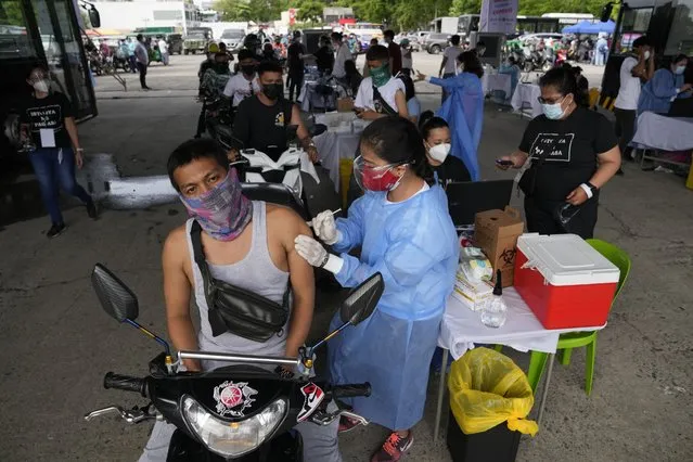 A motorcycle rider is inoculated with China's Sinovac COVID-19 vaccine at a drive-thru vaccination center in Manila, Philippines, Tuesday, June 22, 2021. The Philippine president has threatened to order the arrest of Filipinos who refuse COVID-19 vaccination and told them to leave the country for hard-hit countries like India and the United States if they would not cooperate with massive efforts to end the pandemic. (Photo by Aaron Favila/AP Photo)