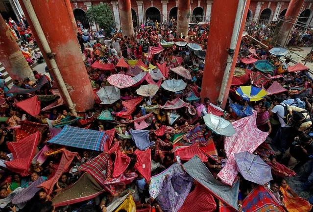 Hindu devotees hold up clothes and umbrellas to receive rice as offerings being distributed by a temple authority on the occasion of the Annakut festival in Kolkata, India, November 8, 2018. (Photo by Rupak De Chowdhuri/Reuters)
