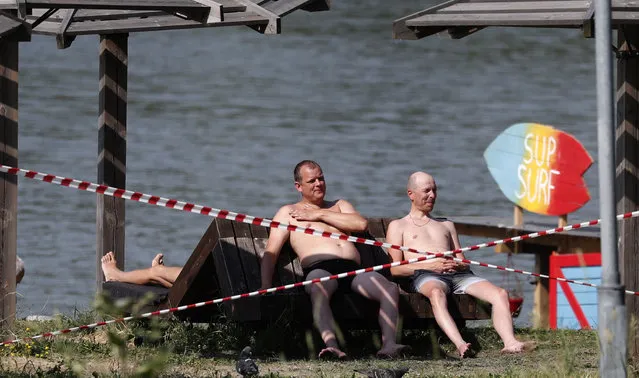 Russians spend time outdoors during sunny hot weather on a closed beach at a pond, in Moscow, Russia, 23 June 2021. (Photo by Maxim Shipenkov/EPA/EFE)