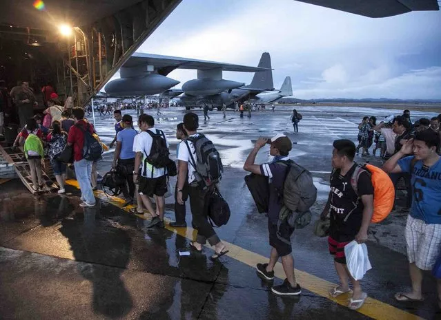 In this Tuesday, November 12, 2013, photo provided by the Navy Media Content Service (NMCS), civilians displaced by Typhoon Haiyan board a U.S. Marine Corps KC-130J Super Hercules at Tacloban Air Base before being transported to Manila, Philippines. U.S. service members are assisting the Armed Forces of the Philippines joined the recovery efforts for the people affected in the aftermath of Typhoon Haiyan. (Photo by Lance Cpl. Anne K. Henry/AP Photo/NMCS/Released)