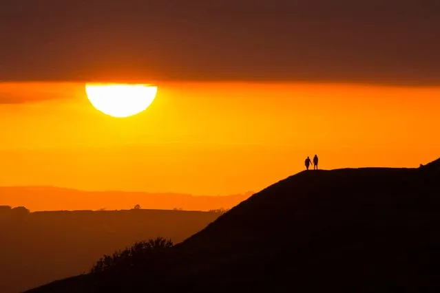 Walkers on Eggardon Hill at Askerswell, Dorset, United Kingdom get a spectacular view of the sunset on June 3, 2021. (Photo by Graham Hunt/Alamy Live News)