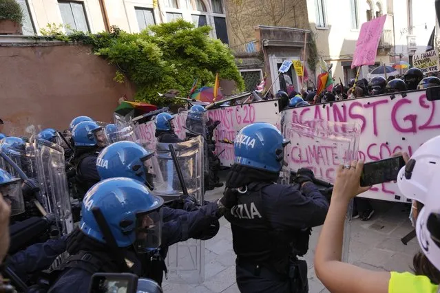 Italian Policemen in riot gears clash with demonstrators during a protest against the G20 Economy and Finance ministers and Central bank governors' meeting in Venice, Italy, Saturday, July 10, 2021. (Photo by Luca Bruno/AP Photo)