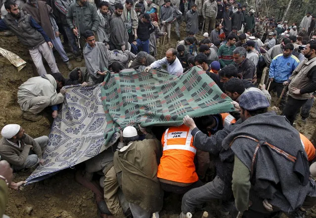 Villagers and rescue workers use blankets to cover the bodies of victims amongst the rubble after a hillside collapsed onto a house at Laden village, west of Srinagar, March 30, 2015. India is experiencing more extreme rainfall events as the global climate warms, a study of 50 years of data by the Indian Institute of Tropical Meteorology concluded. (Photo by Danish Ismail/Reuters)