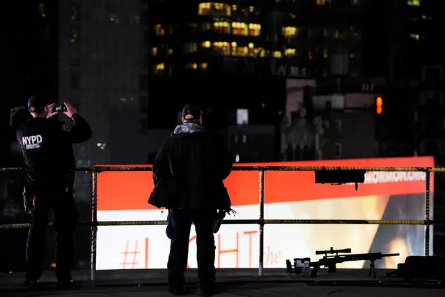 New York Police Department counter-snipers stand on a hotel balcony as they look at the New Year's Eve festivities in Times Square below in New York, December 31, 2016. (Photo by Mark Kauzlarich/Reuters)