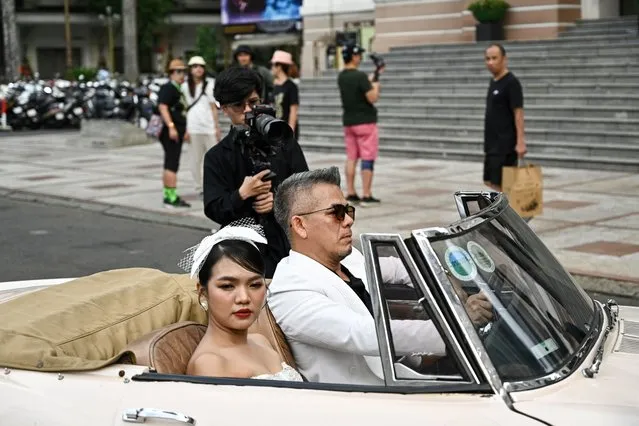 A couple poses for wedding photos in front of the Saigon Opera House in Ho Chi Minh City on December 7, 2023. (Photo by Nhac Nguyen/AFP Photo)