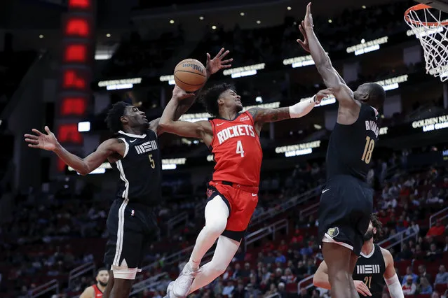 Houston Rockets guard Jalen Green (4) attempts to dunk between Memphis Grizzlies guard Vince Williams Jr. (5) and center Bismack Biyombo (18) during the first half of an NBA basketball game Wednesday, December 13, 2023, in Houston. (Photo by Michael Wyke/AP Photo)