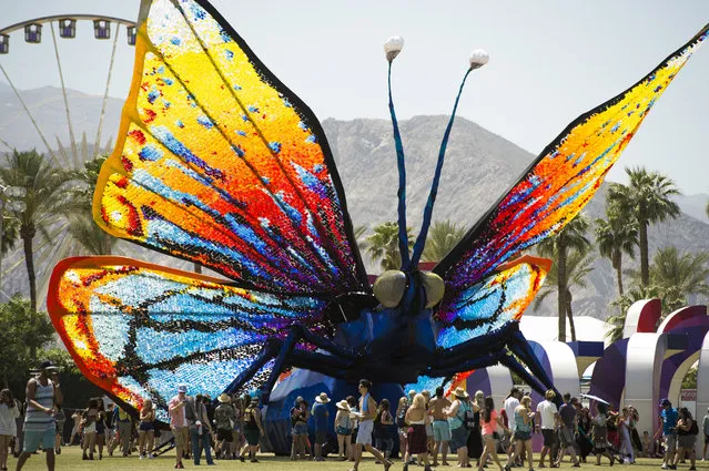 Concert attendees walk past a giant butterfly sculpture on the main grounds on day three of the Coachella Music Festival in Indio, California on April 12, 2015. (Photo by Robyn Beck/AFP Photo)