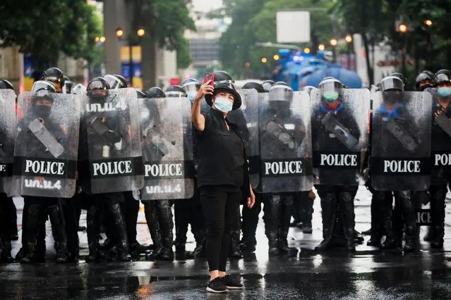 A woman takes a selfie next to police officers as she attends a protest over the government's handling of the coronavirus disease (COVID-19) pandemic, near the police headquarter in Bangkok, Thailand, August 17, 2021. (Photo by Soe Zeya Tun/Reuters)