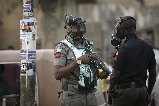 Riot policeman wear gas masks and carry a tear gas grenade launcher, but did not fire, during a celebratory gathering of supporters of President Muhammadu Buhari anticipating victory, in Kano, northern Nigeria Monday, February 25, 2019. Nigeria's electoral commission on Monday began announcing official results from the country's 36 states as President Muhammadu Buhari seeks a second term. (Photo by Ben Curtis/AP Photo)