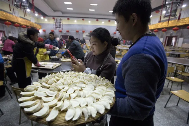 A woman shows the photo she took of a man holding dumplings during a community gathering ahead of the Chinese lunar new year at a village on the outskirts of Beijing, China, Thursday, January 26, 2017. Chinese in mainland China hand make and eat dumplings to mark the start of the Year of the Rooster on Jan 28, 2017. (Photo by Ng Han Guan/AP Photo)