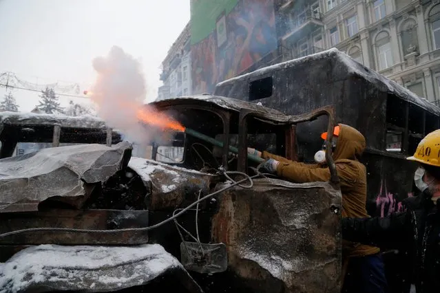 Protesters use fireworks during clashes with police in central Kiev, Ukraine, early Wednesday, January 22, 2014. Two people have died in clashes between protesters and police in the Ukrainian capital Wednesday, according to medics on the site, in a development that will likely escalate Ukraine's two month-long political crisis. (Photo by Sergei Grits/AP Photo)