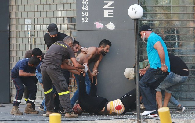 People evacuate a man who was shot while trying to fire a rocket-propelled grenade during a gunfire in Beirut, Lebanon on October 14, 2021. (Photo by Aziz Taher/Reuters)