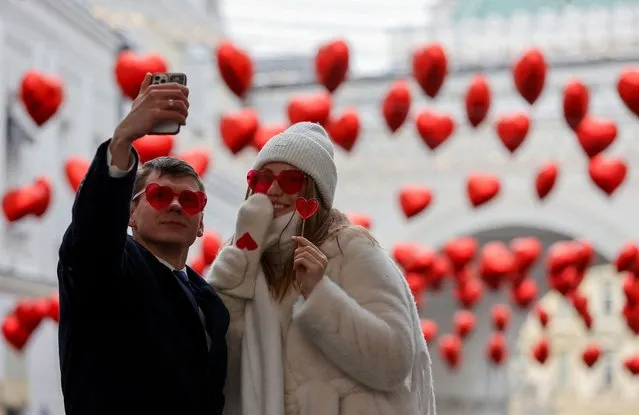 A couple poses for a selfie in a decorated street on Valentine's Day in Moscow, Russia on February 14, 2024. (Photo by Yulia Morozova/Reuters)
